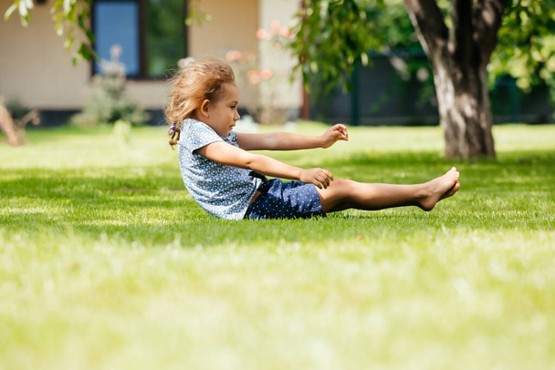 Active little girl makes a somersault on the backyard - Photo, Image
