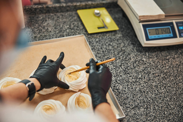 Professional confectioner adding icing and glaze to white meringues - Foto, Bild