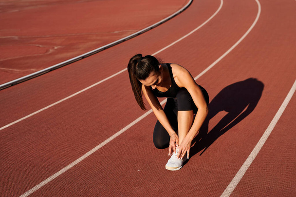 sportswoman in the stadium laces up her laces - Foto, immagini