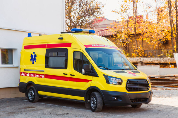 Zaporozhye, Ucrania- 08 de noviembre 2019: Paradas de ambulancia amarilla cerca del edificio del hospital. Vista lateral. - Foto, Imagen