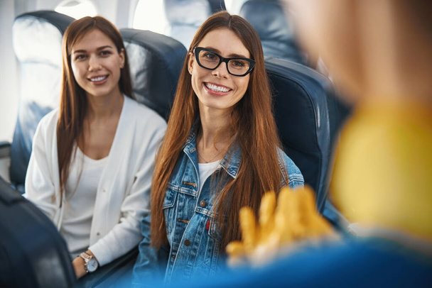 Friendly ladies smiling to the stewardess during the flight - Zdjęcie, obraz