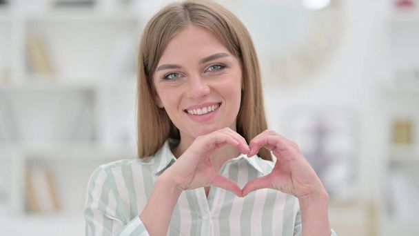 Porträt einer glücklichen jungen Frau mit Herzzeichen und Hand - Foto, Bild