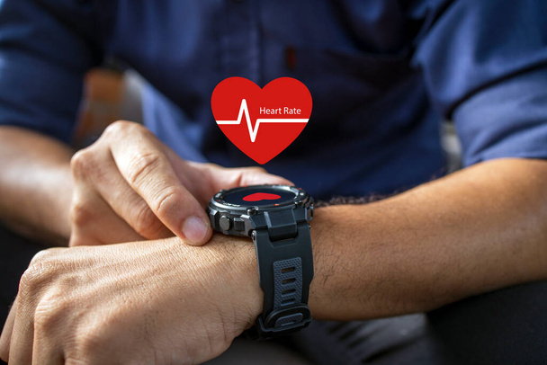 male hand holding wearing smart watch showing heart rate icon with soft-focus and over light in the background. - Photo, Image
