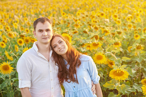 Usmívající se šťastný novomanželský pár na poli slunečnic. Koncept lásky, vzájemného respektu a správných vztahů - Fotografie, Obrázek