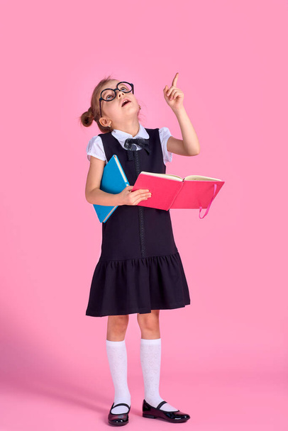 preschool girl with glasses holding a book, raised her hand and - Φωτογραφία, εικόνα