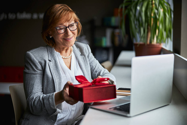 Delighted mature woman holding red box with present - Photo, Image