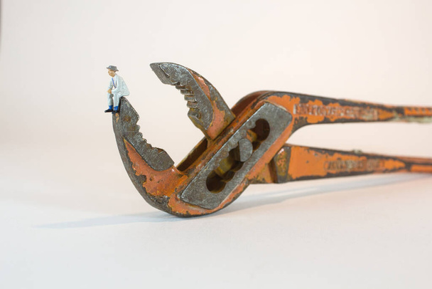 A minifigure of a man sitting on a rusty adjustable wrench - Zdjęcie, obraz