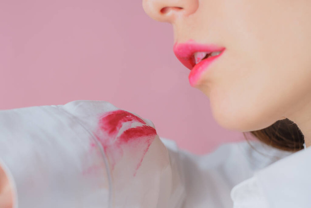 грязное пятно от помады, оставленное женщиной на белой рубашке. изолированные на розовом фоне - Фото, изображение