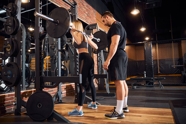 Professional gym instructor assisting woman at the gym - Photo, image