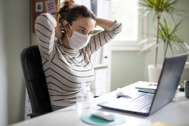 Young business woman wearing protective mask, working at home office. Working from home during the epidemic - Zdjęcie, obraz