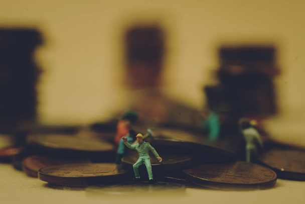 οικονομία και εργασία: μικροσκοπικοί εργαζόμενοι σε κέρματα με κίτρινο φόντο - Φωτογραφία, εικόνα