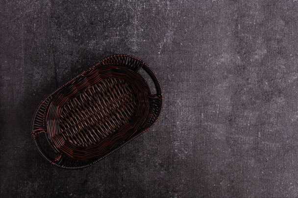 A wicker food basket on a dark background. Basket for bread, appliances. Background for the label - Фото, изображение