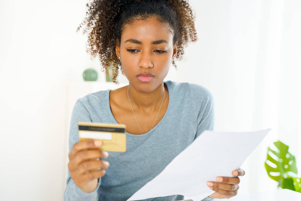 Unhappy black woman feel worried checking credit card expenses - Foto, Imagen
