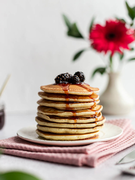 A stack of pancakes with jam from cones on a light background. A plate of pancakes sits on a pink napkin - Photo, Image