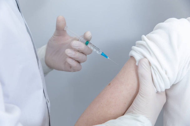 Close up of a Doctor making a vaccination in the shoulder of patient - Фото, зображення