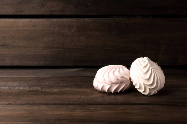 malvavisco. dos merengues redondos sobre fondo de madera oscura con espacio para copiar - Foto, Imagen