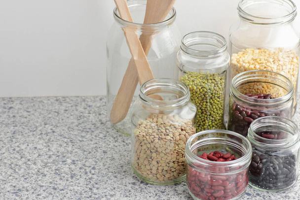 Variety of dry legumes: kidney bean, peas, green gram in glass jars uncooked on white kitchen background, zero waste, eco friendly, balanced diet food, healthy clean eating, vegan protein concept - Foto, Imagem