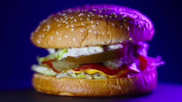 Rotierender rustikaler Hamburger mit Neonhintergrundbeleuchtung. - Filmmaterial, Video