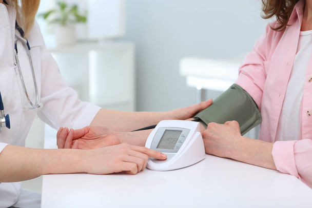 Doctor checking blood pressure of woman in clinic, closeup - Фото, зображення