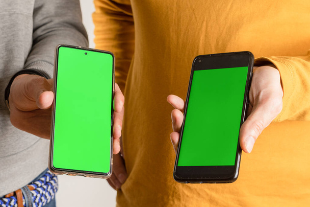 Deux personnes montrent leurs smartphones avec écran vert - Photo, image