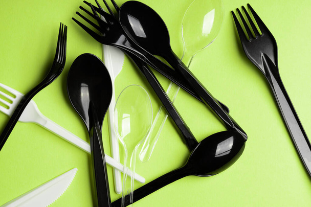 ピンクの背景にフォーク、スプーン、ナイフ。プラスチック刃物、生態系、プラスチックによる環境汚染、使い捨て食器、廃棄物リサイクルの概念。パターン、フラットレイアウト - 写真・画像