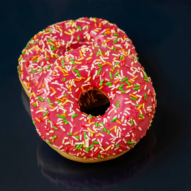 Two bright glazed donuts on dark minimal background, top view - Foto, Imagem