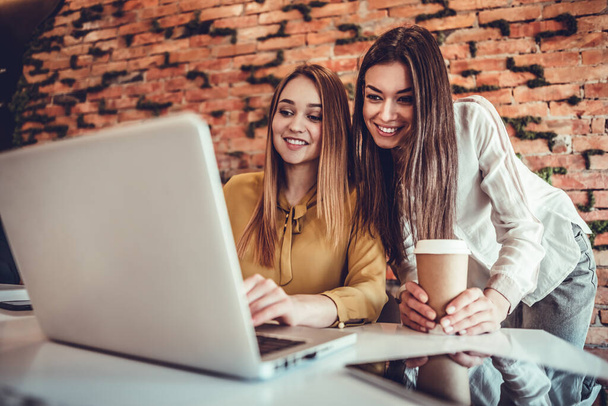 Two young women working together at startup office planning new business on brick wall background - Foto, Bild