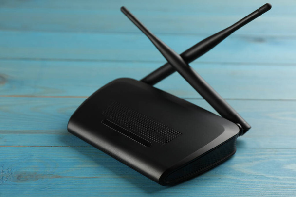 Modern Wi-Fi router on light blue wooden background - Fotó, kép