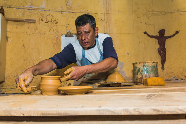 Mexikanischer Töpfer, der den Ton in seiner Werkstatt mit den Händen bearbeitet, um Skulpturen, Vasen, Krüge, Vasen usw. nach traditionellen Methoden herzustellen. - Foto, Bild