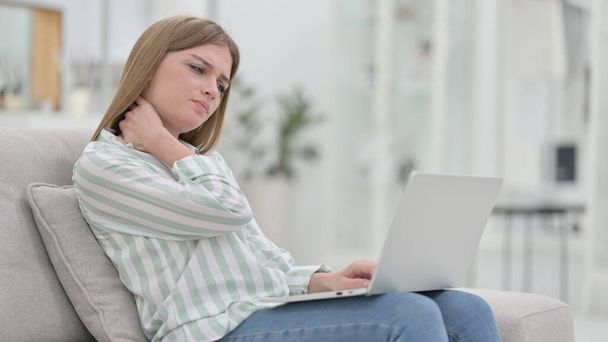 Zmęczona młoda kobieta z laptopem ma ból szyi w domu  - Zdjęcie, obraz