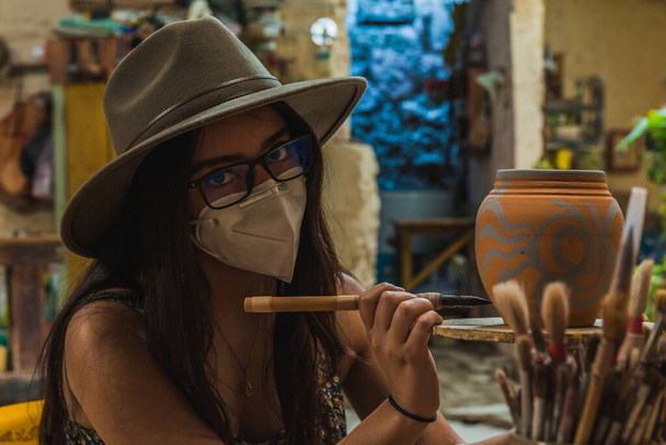Abenteuerlustiges Touristenmädchen, das in einer Töpfer- und Tonwerkstatt das Malen lernt. - Foto, Bild