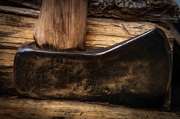 Dark moody rustic worn axe with chopped wood for fire during cold weather - Photo, Image