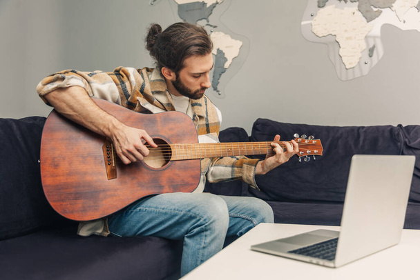 Work from home. A young guy is learning to play the guitar. Online guitar lessons. E-learning. Distance learning. - Fotoğraf, Görsel