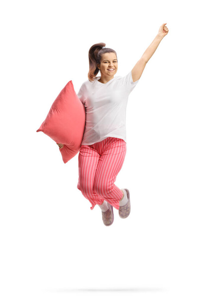 Ευτυχισμένη γυναίκα με πιτζάμες που κρατάει ένα μαξιλάρι και πηδάει απομονωμένη σε λευκό φόντο - Φωτογραφία, εικόνα
