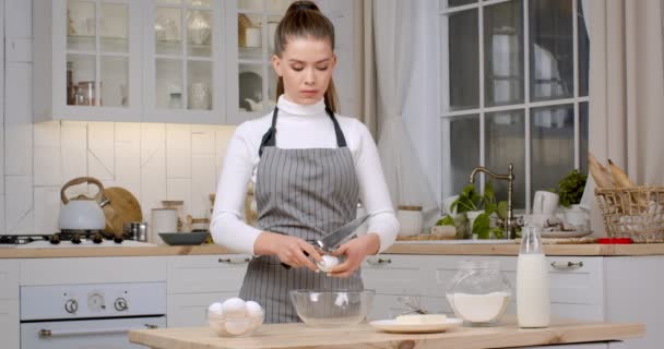 Cuisson domestique. Jeune femme confiseur préparant la pâtisserie à la maison, battant les œufs pour la pâte, debout à la cuisine - Séquence, vidéo