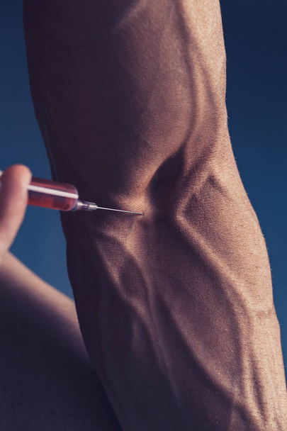 a muscular man with a syringe - 写真・画像