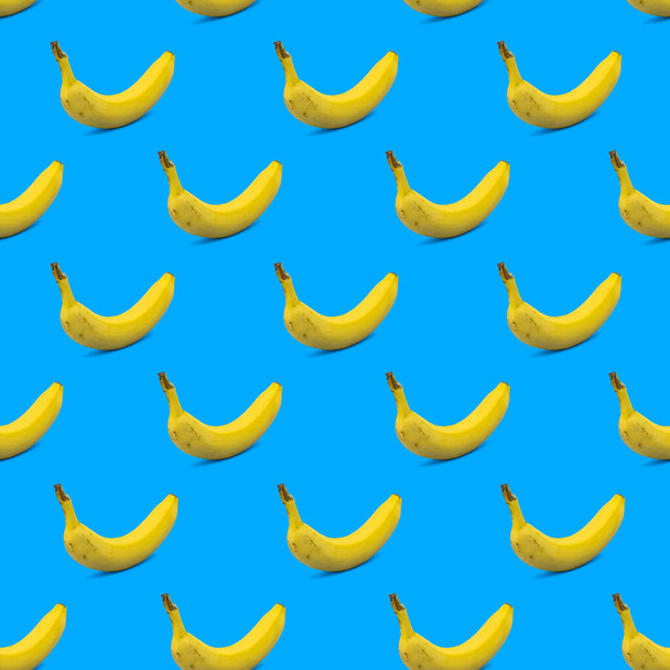 Padrão de fundo colorido e de verão ilustração de sombra de carcaça de banana fresca amarela na superfície azul. Conceito mínimo de comida de verão - Foto, Imagem