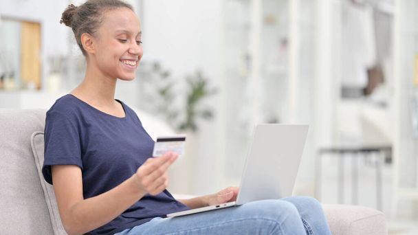Online betaling succes op laptop voor Afrikaanse vrouw thuis  - Foto, afbeelding