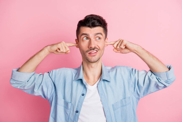 Photo portrait of young man closed ears with fingers looking at blank space ignoring refusing isolated pastel pink color background - Fotoğraf, Görsel