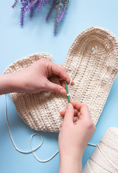Hands crochet a bag made of white cotton cord on a blue background. Hobby, handmade. - Fotoğraf, Görsel