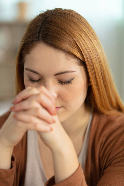 young woman at home with her eyes closed in prayer - Photo, image