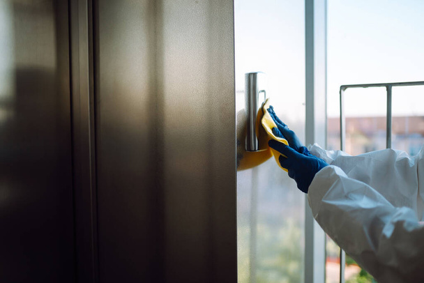 Cleaning and disinfection of the elevator to prevent COVID-19. Worker wearing protective suit sprays disinfectant buttons of the lift.  - Zdjęcie, obraz