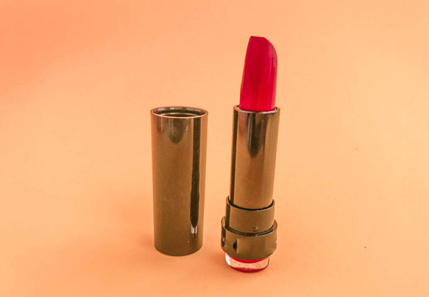 Beautiful fashionable beauty cosmetic glamorous red lipstick for applying makeup on the lips on a yellow gentle background. - Photo, Image