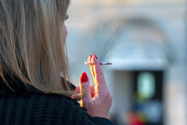 Een vrouw rookt een sigaret op straat. Slechte gewoonte. - Foto, afbeelding
