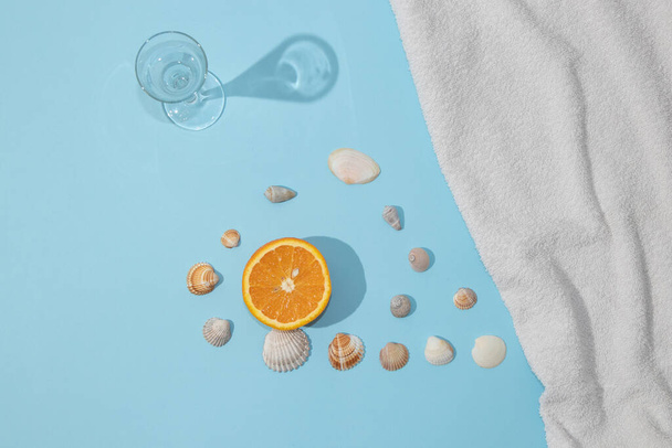 Scène estivale avec serviette de plage bleu vif et verre et fruits et coquille orange. Concept de boisson froide ou de rafraîchissement. - Photo, image