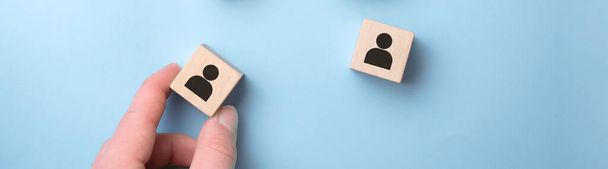 Hand picked a wooden cubes with person icon on blue background, Organisation structure, social network, leadership, team building, recruitment business, management and human resources concepts. - Foto, imagen
