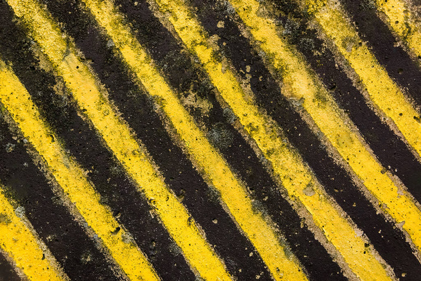 Vaarallisten rajoitettujen alueiden määrittely, mustat ja keltaiset lävistyslinjat betonimateriaalilla. - Valokuva, kuva
