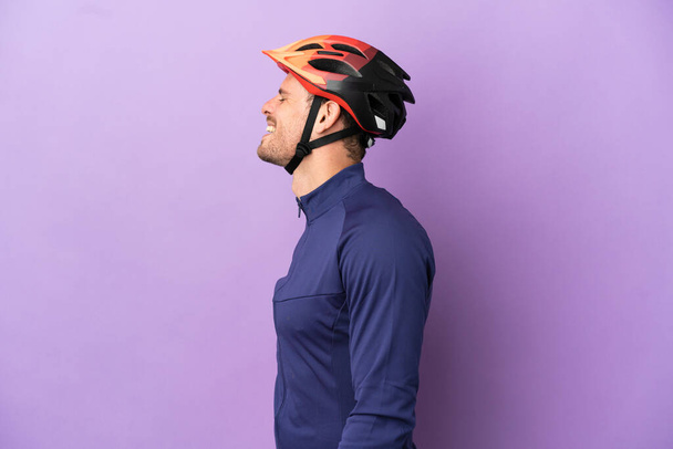 Young Brazilian cyclist man isolated on purple background laughing in lateral position - Photo, Image