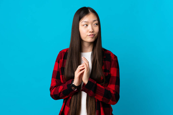 Fiatal kínai lány elszigetelt kék háttér tervez valamit - Fotó, kép