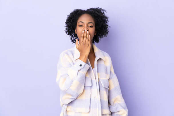 手で口をカバー紫色の背景に隔離された若いアフリカ系アメリカ人女性 - 写真・画像